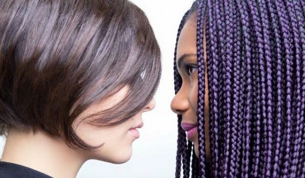 deux femmes se font face en gros plan et de profil une blanche coiffée court avec une mèche et une autre noire coiffées de nattes longues finement tressées